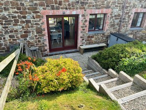Een stenen gebouw met een houten bankje en een kleine tuin vol planten en bloemen.
