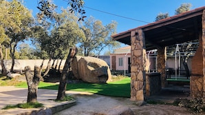 A stone building with a tiled roof, a paved walkway, and a large rock in the foreground.