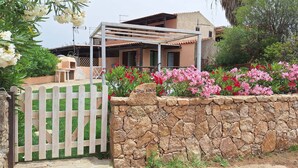 Un mur de pierre avec une porte en bois, une pergola et une maison avec un toit en tuiles.
