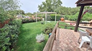 Un jardin bien entretenu, agrémenté d’une pergola, d’une terrasse en briques et de mobilier d’extérieur.