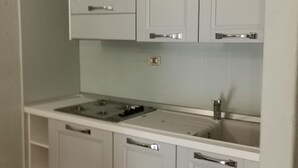 Une cuisine avec des meubles blancs, un évier à deux bacs et une cuisinière.