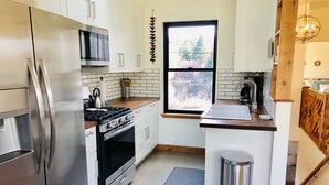 Una cocina moderna con electrodomésticos de acero inoxidable, una ventana con vistas y una pared de acento de madera.
