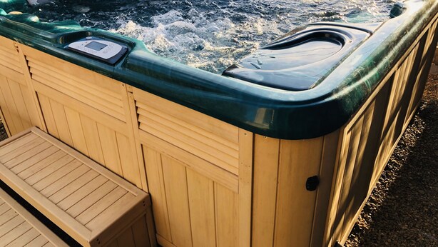 Una bañera de hidromasaje de madera con panel de control y un banco de madera.