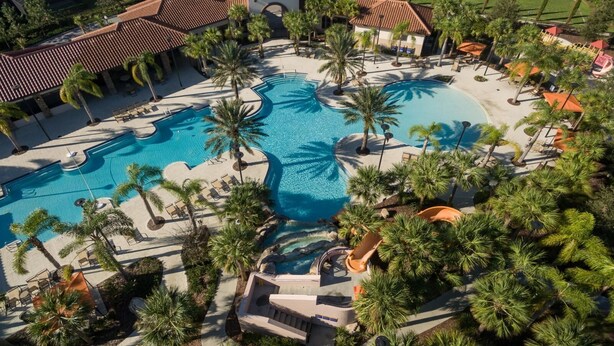 An aerial view of a resort with multiple swimming pools, palm trees, and a well-maintained lawn. - 5Star Resort/Clean and Safe/Mins to Parks/WaterPark/Arcade/Bar/Gym/Golf/AC/WiFi (Davenport)