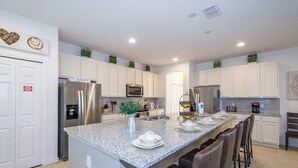 A modern kitchen with white cabinets, stainless steel appliances, and a granite countertop. - 5Star Resort/Clean and Safe/Mins to Parks/WaterPark/Arcade/Bar/Gym/Golf/AC/WiFi (Davenport)