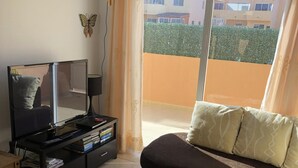 Un salon avec un canapé, un téléviseur et une petite table.