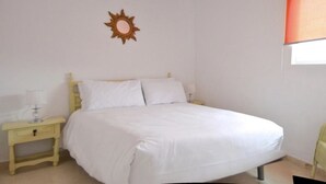 Une chambre à coucher avec un lit, une table de chevet, une lampe et une chaise.