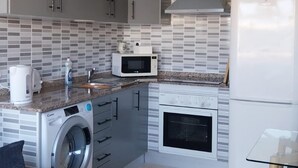 Une cuisine compacte équipée d’un lave-linge, d’un four à micro-ondes et d’un four encastré.