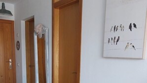 Un coin repas comprenant une table à plateau en verre, quatre chaises grises et une porte en bois.