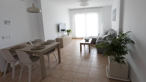 Een moderne woonkamer met een bank, een salontafel en een eetgedeelte met stoelen en een tafel.