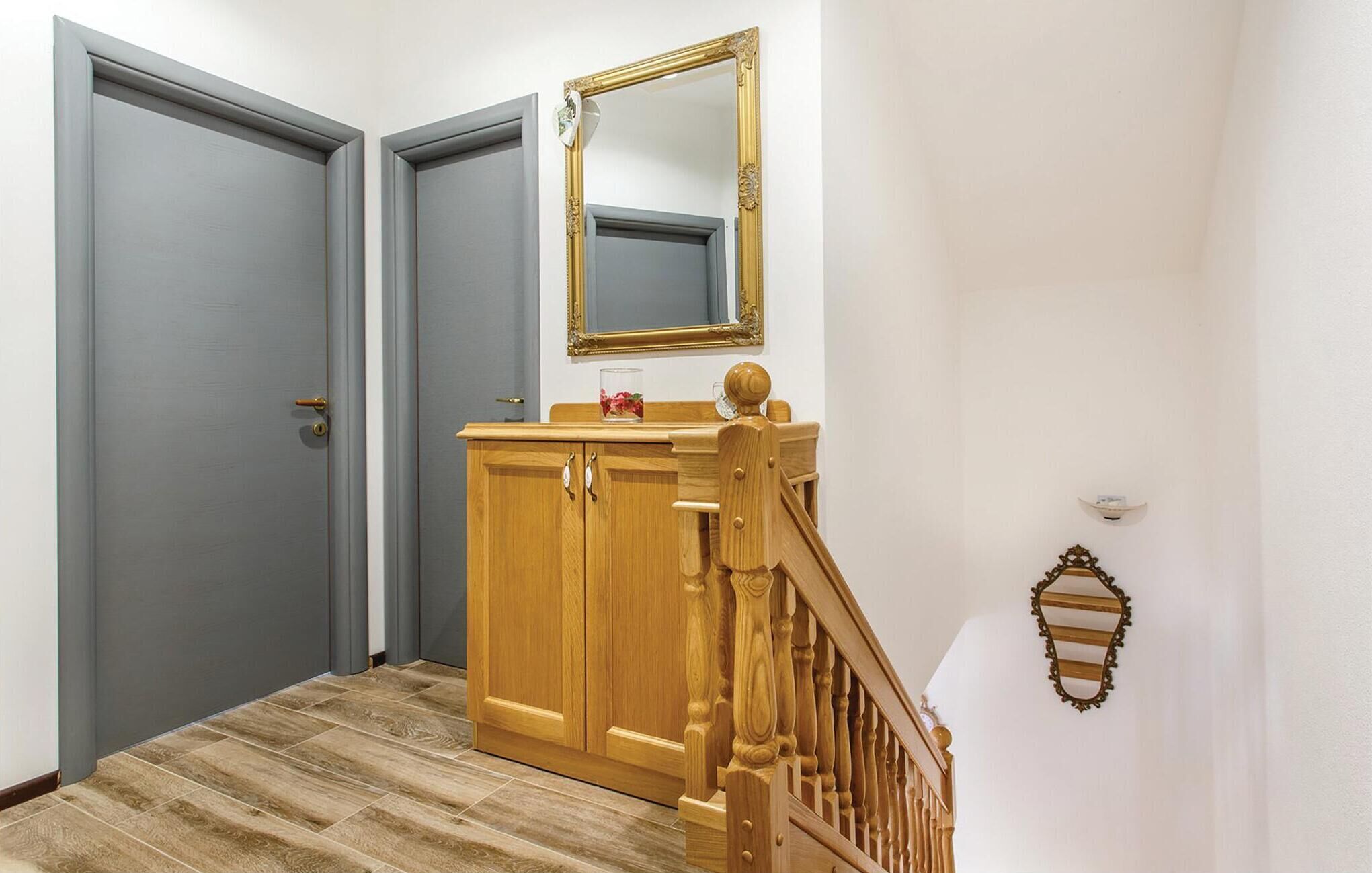 A hallway with a wooden cabinet, a mirror, and a staircase.
