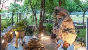 A garden with a water fountain, two swan sculptures, and a large rock with flowers. - 3 bedroom amazing home in Grab (Grab)