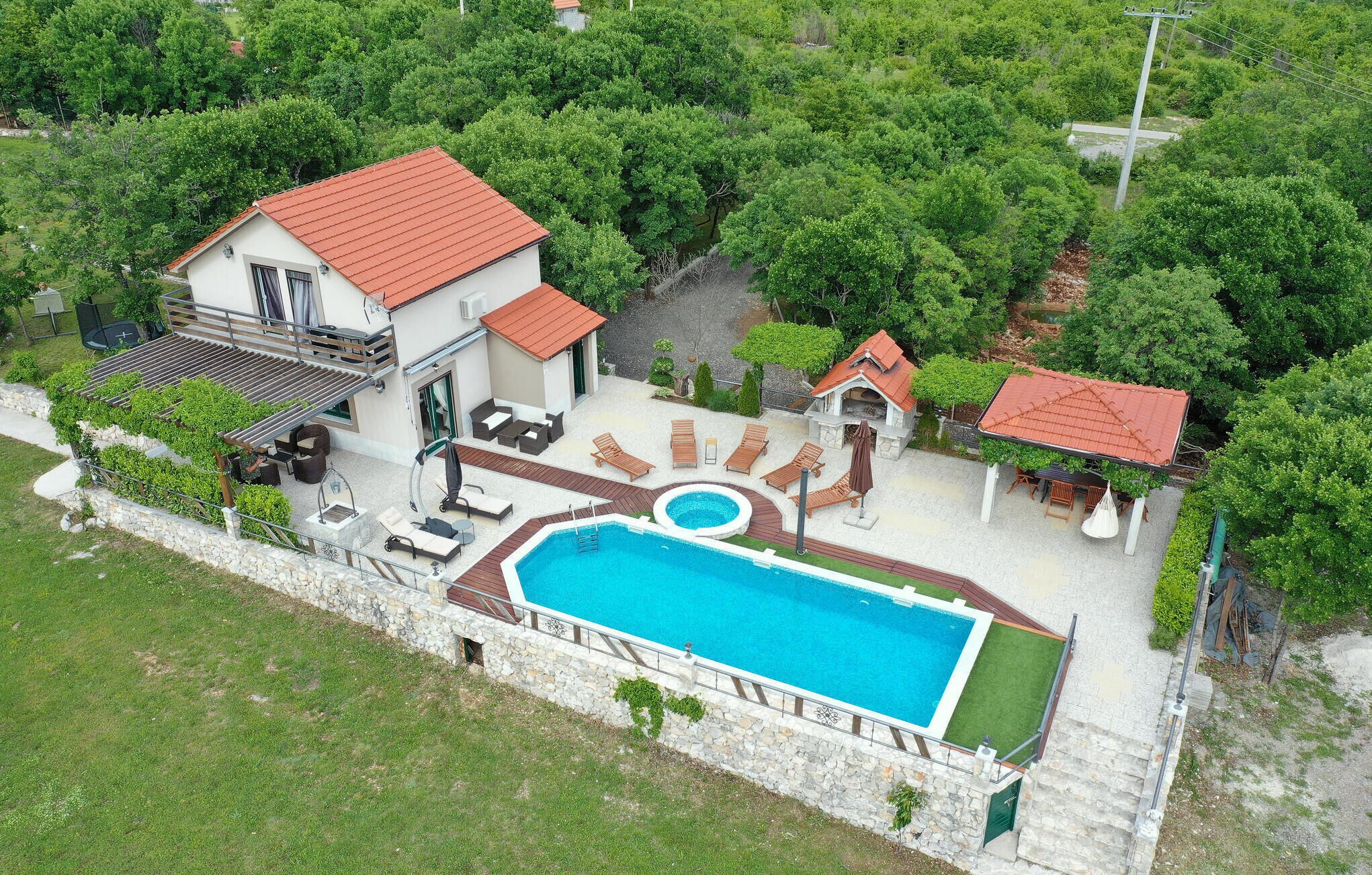 Una casa con piscina, mobiliario de exterior y jardín.