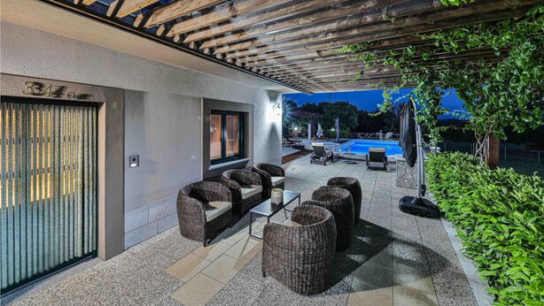 A covered outdoor seating area with wicker furniture, a pool in the background, and a pergola overhead. - 3 bedroom amazing home in Grab (Grab)
