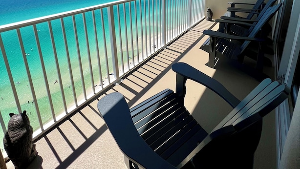 Un balcon avec vue sur l’océan, deux fauteuils et une petite statue.