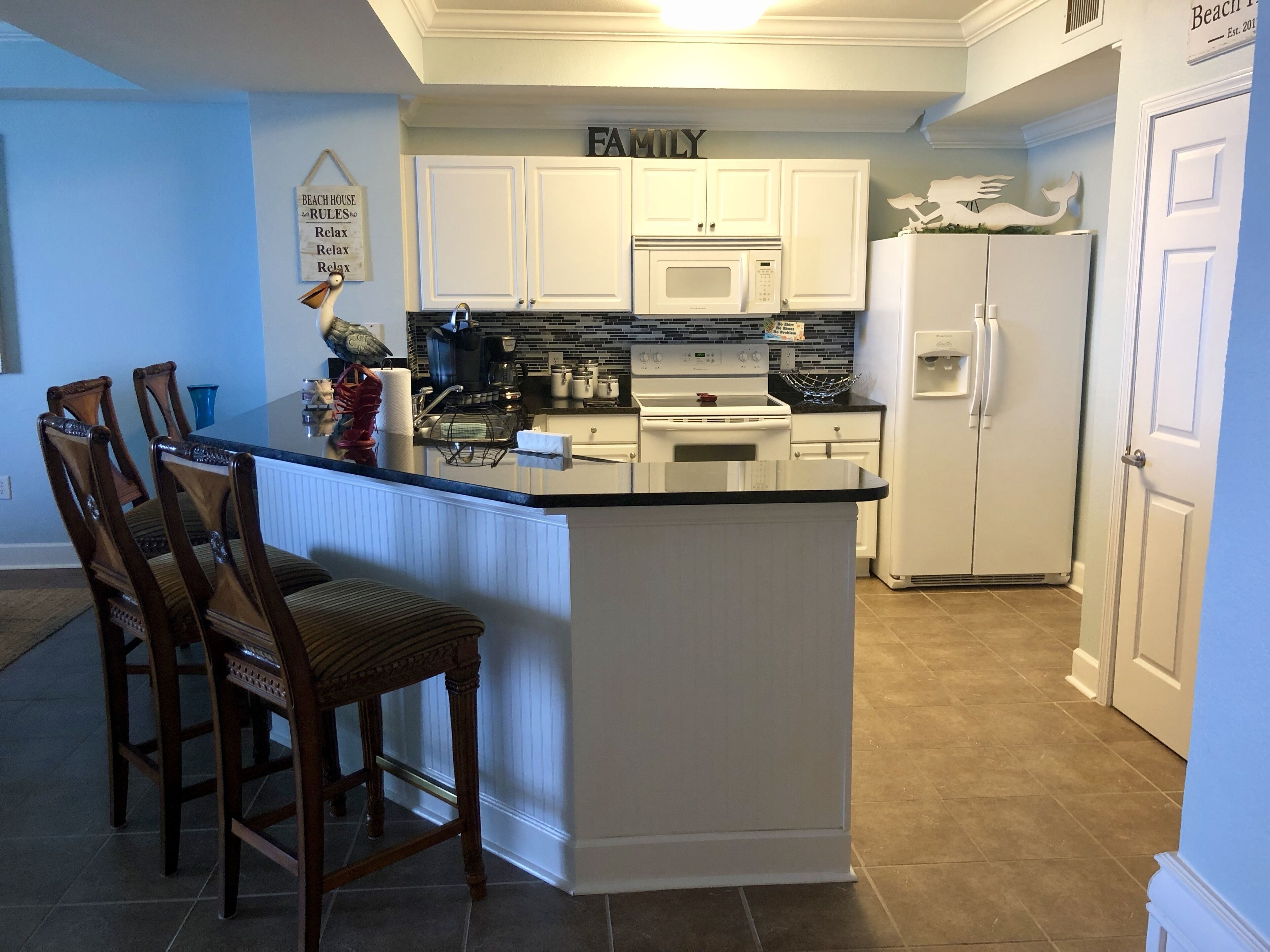 Una cocina con armarios blancos, una isla central y un refrigerador.