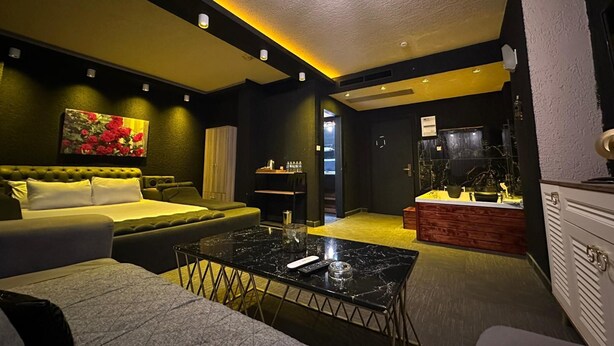Una camera d'hotel moderna con un divano, un tavolino, un mobile e un quadro appeso al muro.