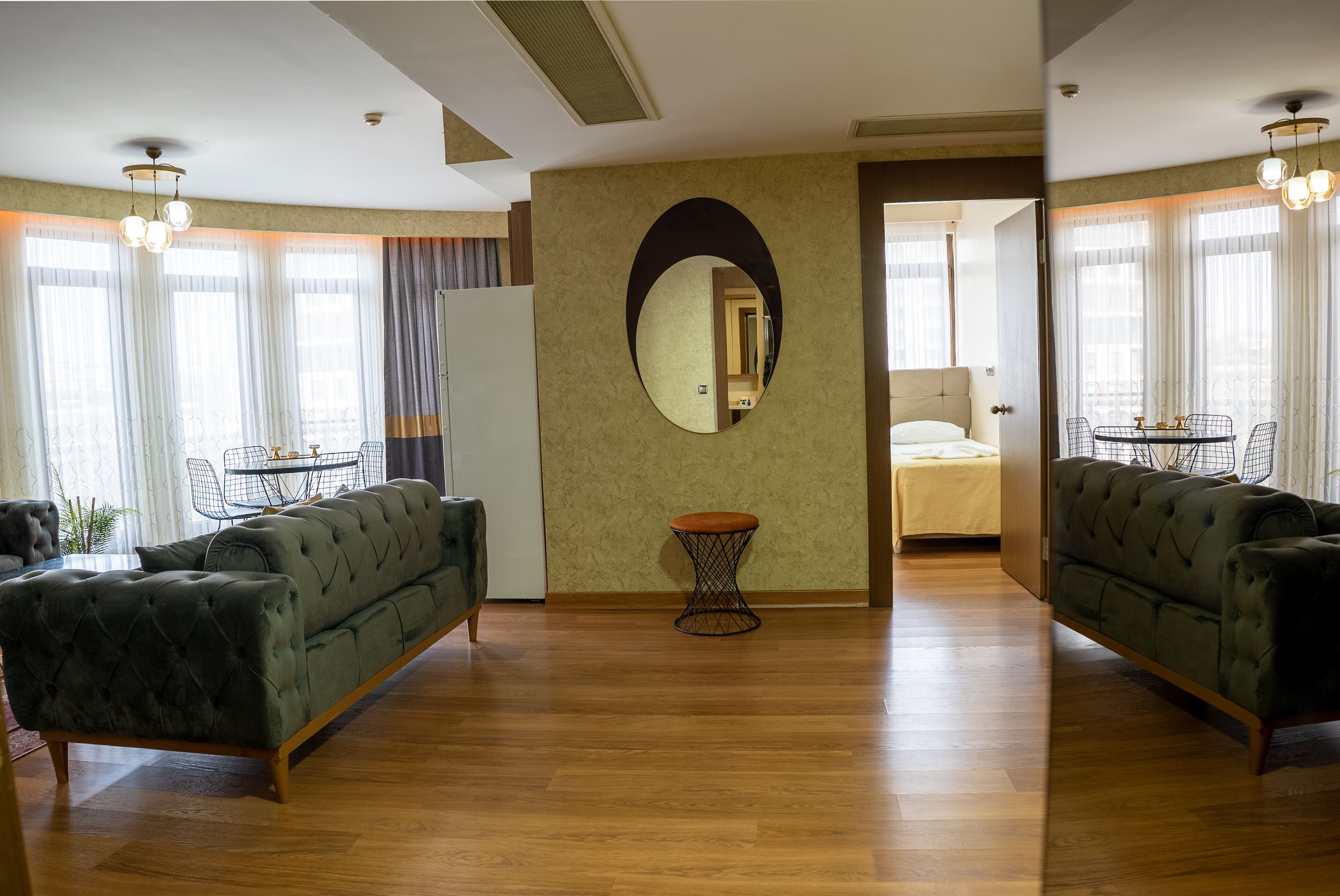 Un salón amplio con un sofá grande, una mesita redonda y un espejo en la pared.