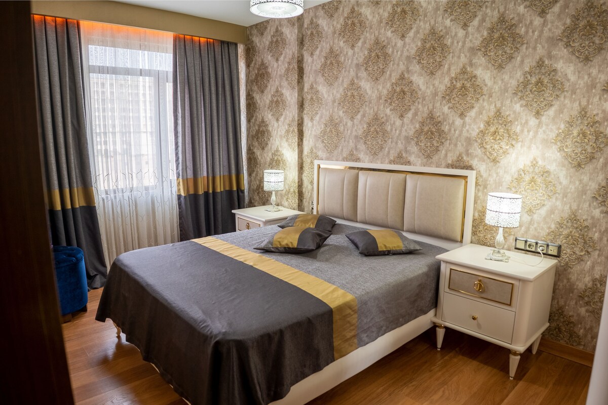 A neatly arranged bedroom with a large bed, two bedside tables, and a nightstand.