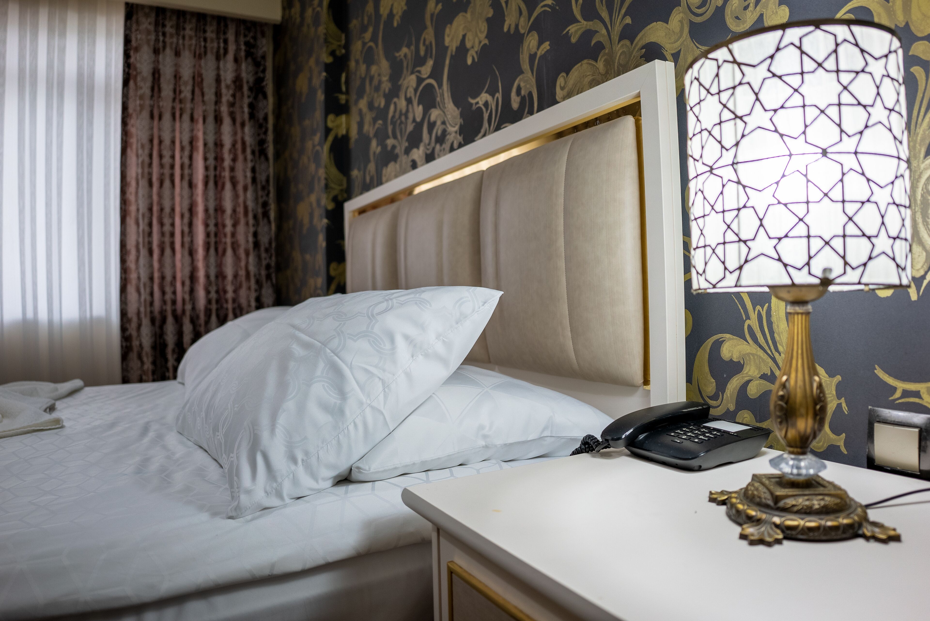 A hotel room with a bed, a bedside telephone, and a lamp.