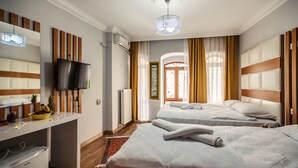 Habitación de hotel con dos camas, un escritorio, un televisor, un refrigerador pequeño y una ventana con cortinas.