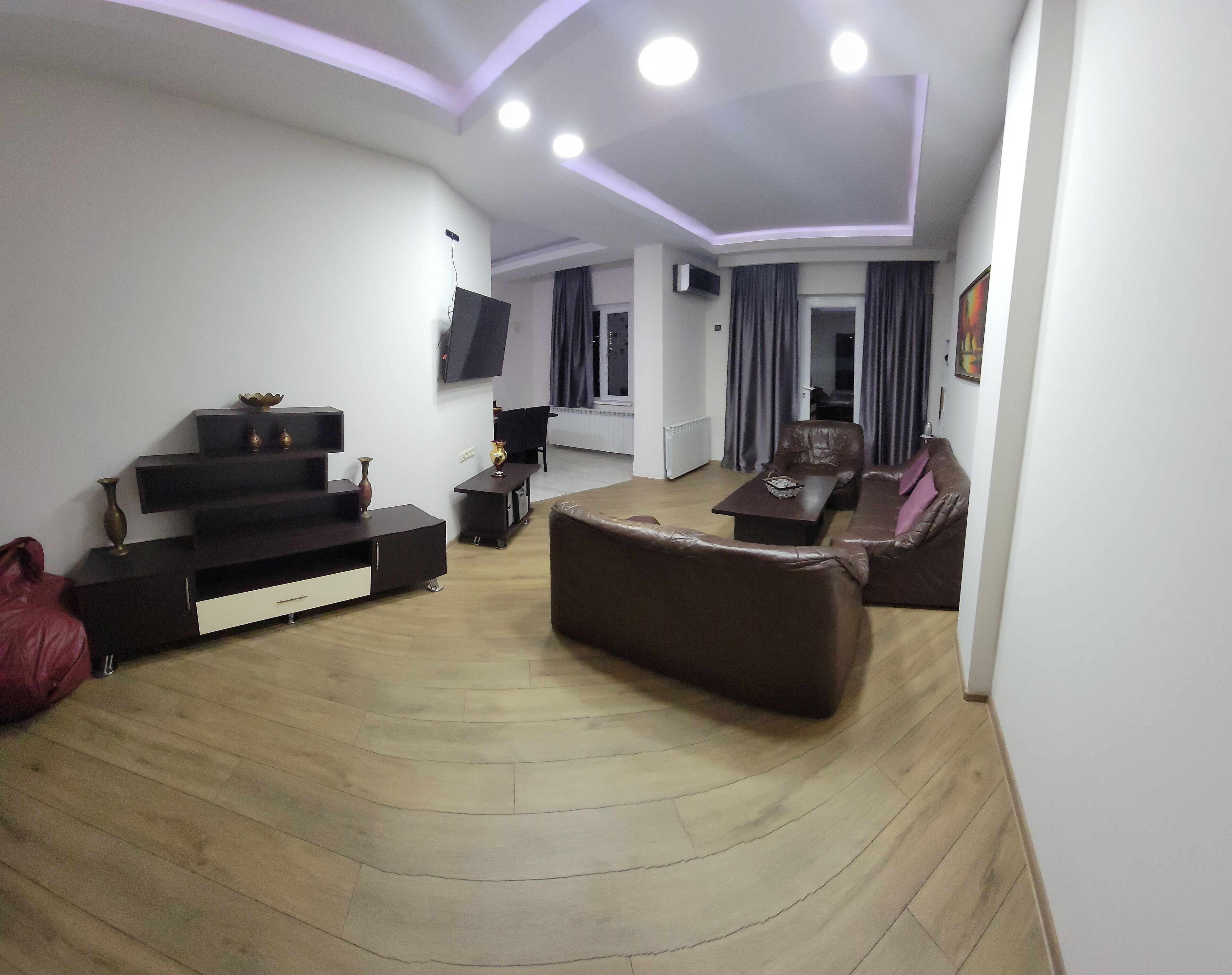 A modern living room with a flat-screen TV, leather sofa, and a coffee table.