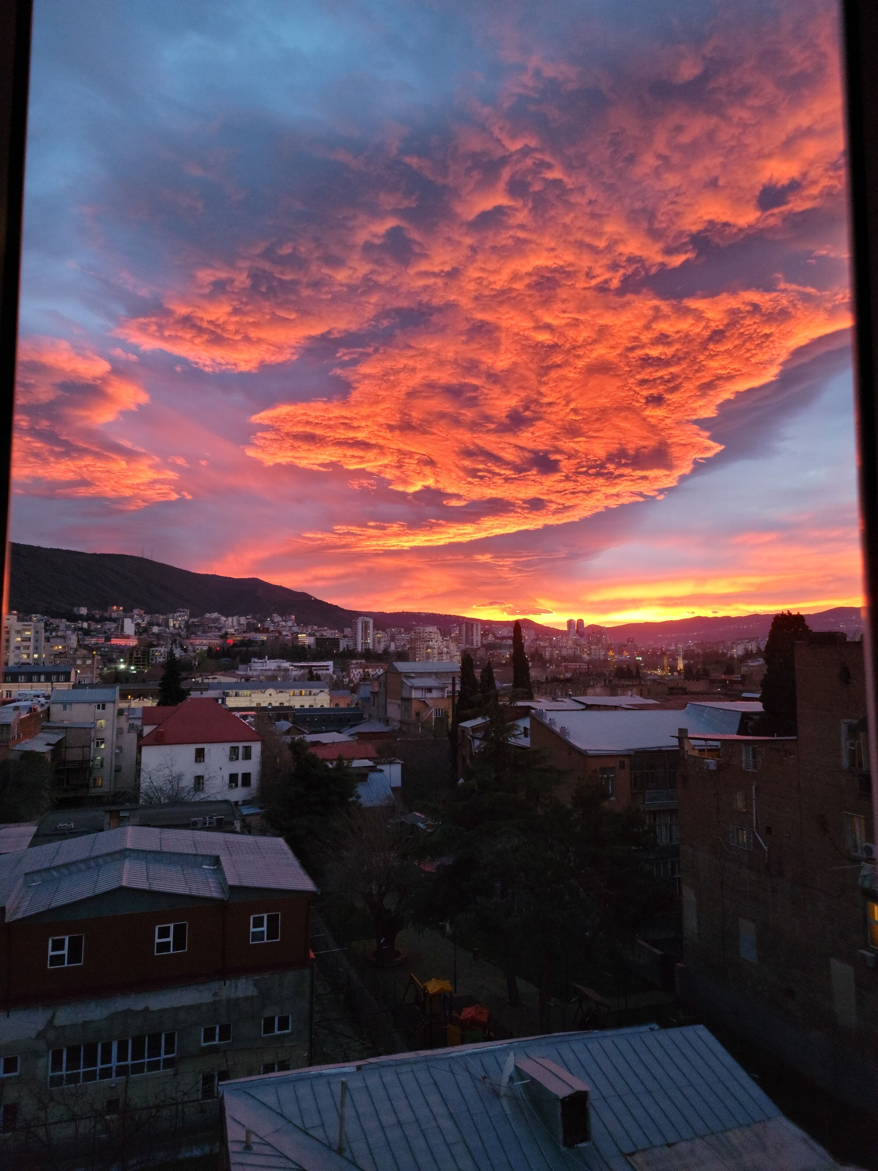Une vue sur une ville au crépuscule, avec un coucher de soleil et des nuages.