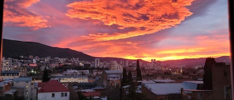 A cityscape at dusk with a sunset and clouds.