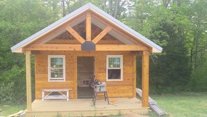 A small wooden cabin with a gabled roof, two windows, and a bench outside. - Bleidt's Buck Cabin (Cadiz)