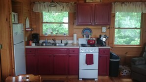 A compact kitchen with wooden cabinets, a refrigerator, a stove, and a sink. - Bleidt's Buck Cabin (Cadiz)