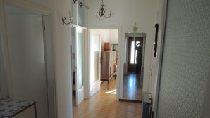 A hallway with wooden flooring, white walls, and a door leading to another room.