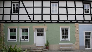 A traditional half-timbered building with a green facade, white doors, and windows. - Vacation apartment Zur alten Schäferei with sauna in the historic four-sided courtyard (Zeulenroda-Triebes)
