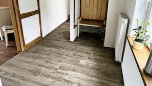A hallway with wooden flooring, a coat rack, a radiator, and a small table with a plant. - Vacation apartment Zur alten Schäferei with sauna in the historic four-sided courtyard (Zeulenroda-Triebes)