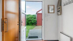 Une porte-fenêtre donnant sur un jardin avec un abri de jardin rouge, un tableau encadré et une prise électrique sur le mur.