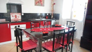 A modern kitchen with red and black cabinetry, a dining table with chairs, and a large window providing natural light.
