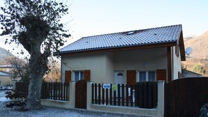 A two-story building with a tiled roof, a wooden fence, and a sign indicating a business.