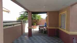 A covered outdoor area with a tiled floor, a table, chairs, and a blue water container. - San Fernando Pampanga (Sanfernando)