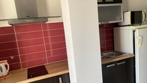 A modern kitchen with red tiles, stainless steel appliances, and dark cabinetry.