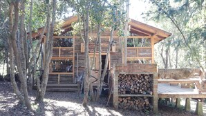 Una cabaña rústica con fachada de madera, chimenea de ladrillo y terraza de madera.