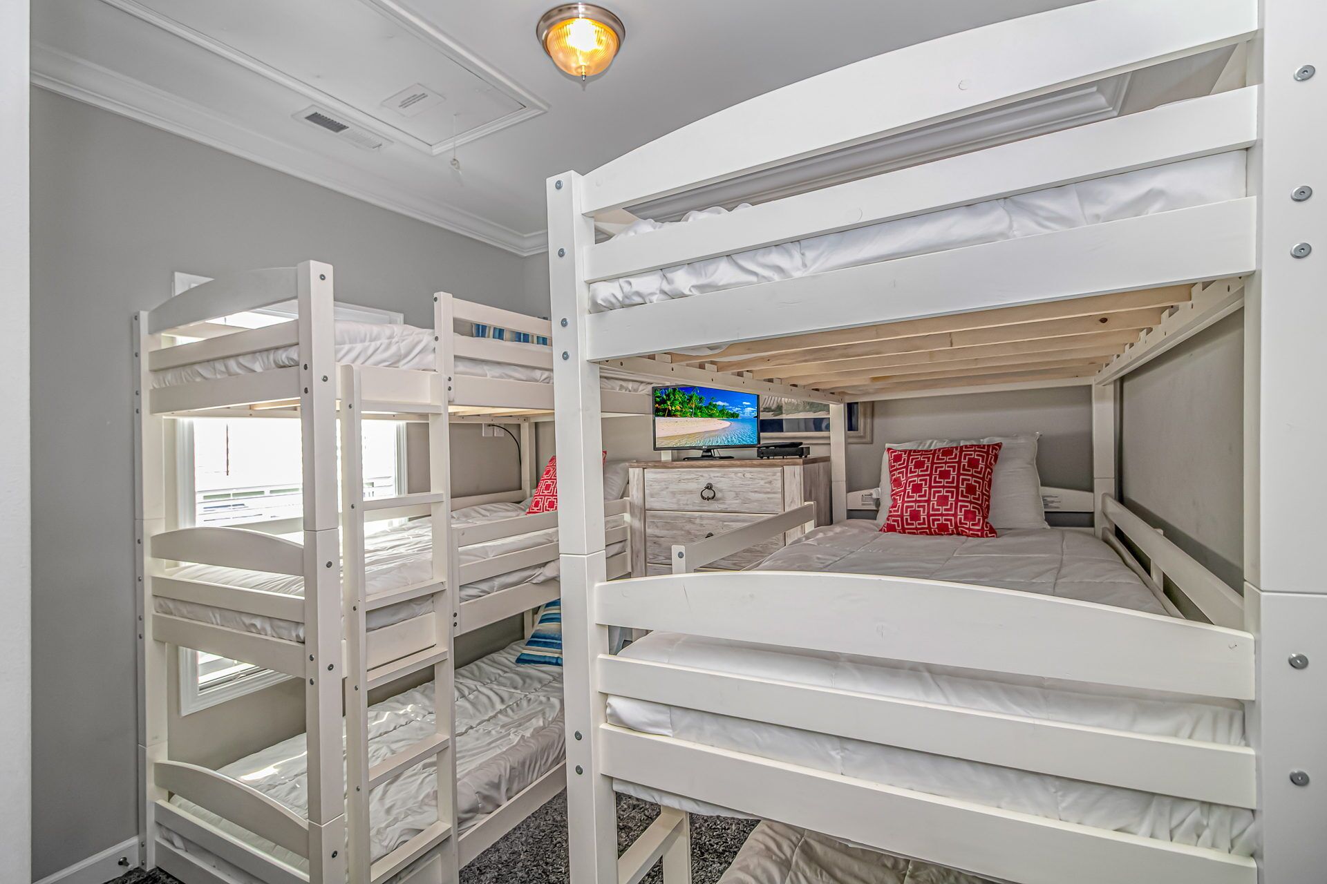 Une chambre avec un lit superposé, une commode et une fenêtre.