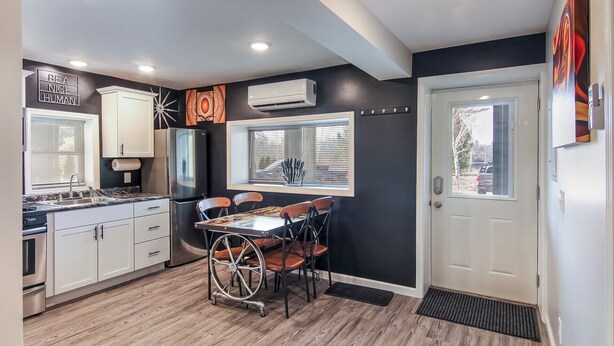 A compact kitchen with white cabinets, a black refrigerator, and a dining table with chairs.