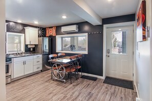 A compact kitchen with white cabinets, a black refrigerator, and a dining table with chairs. - The Hideaway  Interlochen Arts Academy  Sleeping Bear Dunes  Traverse City (Interlochen)