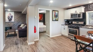 A modern kitchen with stainless steel appliances, a dining area with a wooden table and chairs, and a living area with a sofa and a fireplace.
