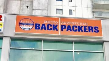 Een gebouw met borden voor 'Metro Adventurer Back Packers' en 'Perette'.