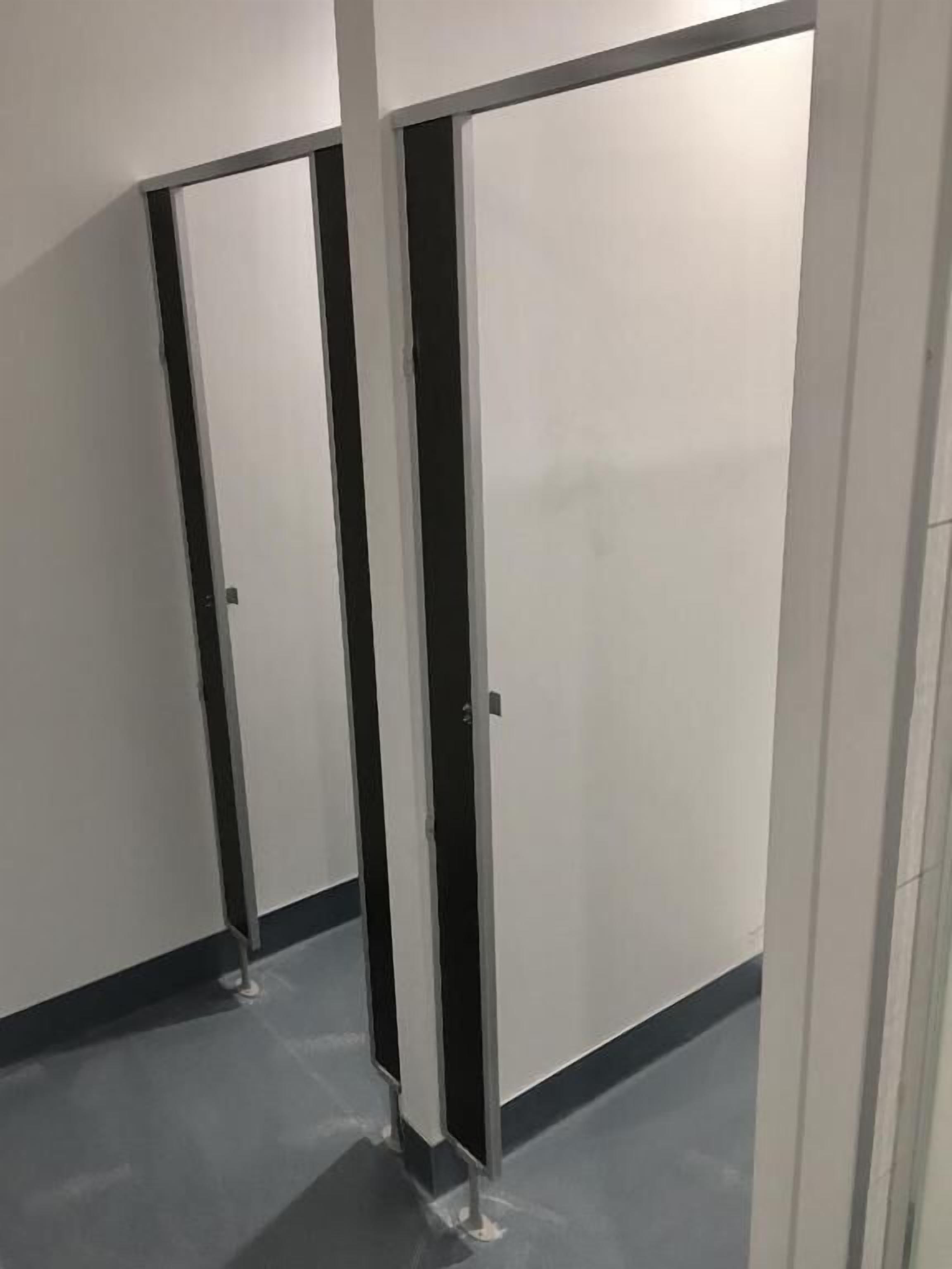 A corridor with closed doors, a tiled floor, and a white wall.