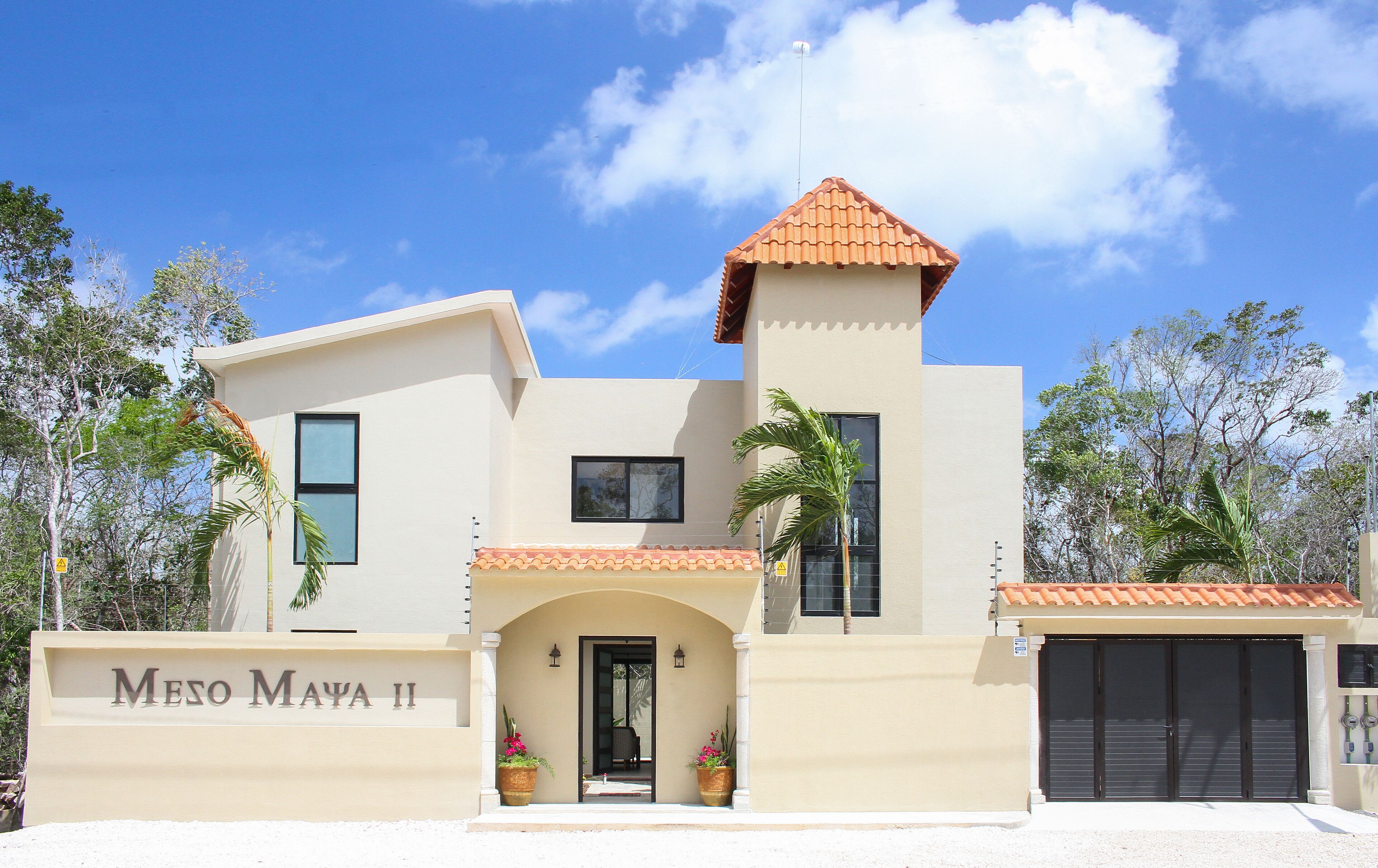 Un bâtiment moderne à deux étages, doté d’une façade beige, d’un toit recouvert de tuiles rouges et d’une enseigne indiquant « Meso Maya II ».