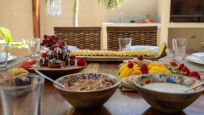 Buffet de l'esmorzar amb diverses fruites, pastissos i bols de cereals damunt d'una taula de fusta.