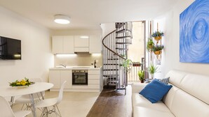 Una cocina moderna con armarios blancos, horno empotrado y comedor con mesa y sillas blancas.