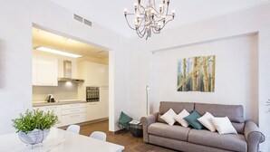 Una sala de estar moderna con un sofá, una mesa de comedor con una planta y una cocina al fondo.
