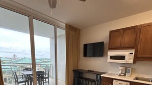 A hotel room with a balcony, a dining area, a kitchen with a microwave, and a ceiling fan. - Welcome to Relaxation! Gulfside Villa 408 (Fort Walton Beach)